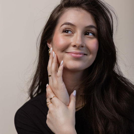 Woman with long dark hair and a black top against a plain background