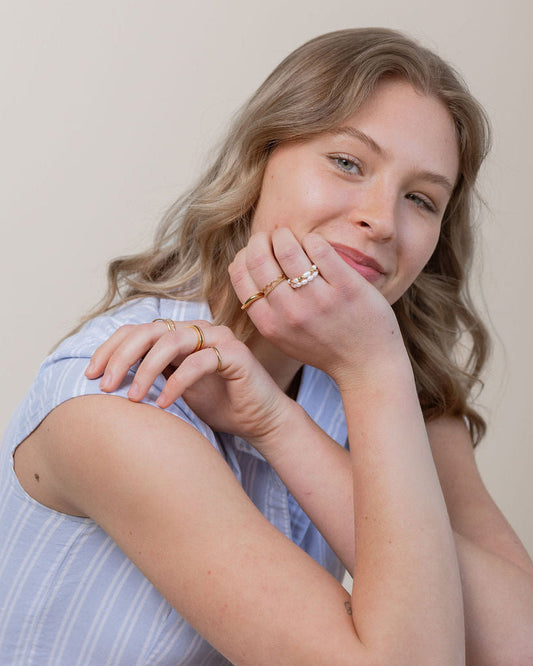 Woman wearing a blue striped shirt and white pants against a plain background