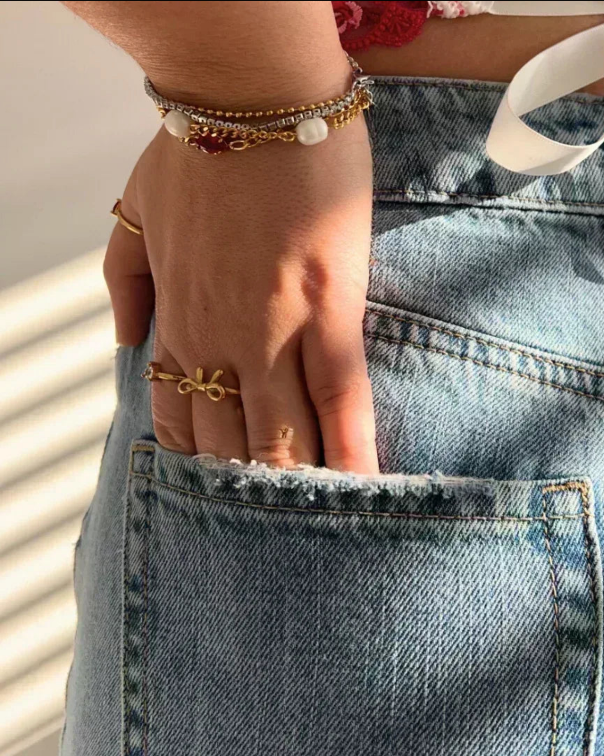 Hand with gold ring and bracelets on a denim background