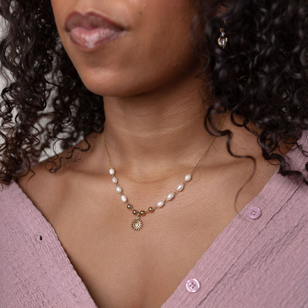 Woman wearing a pearl necklace with a pink blouse