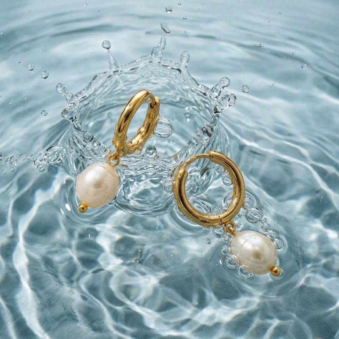 Gold hoop earrings with pearls on a water surface