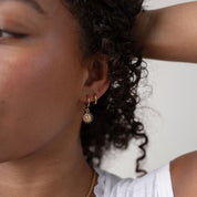 Close-up of a person wearing a white lace top and gold jewelry.